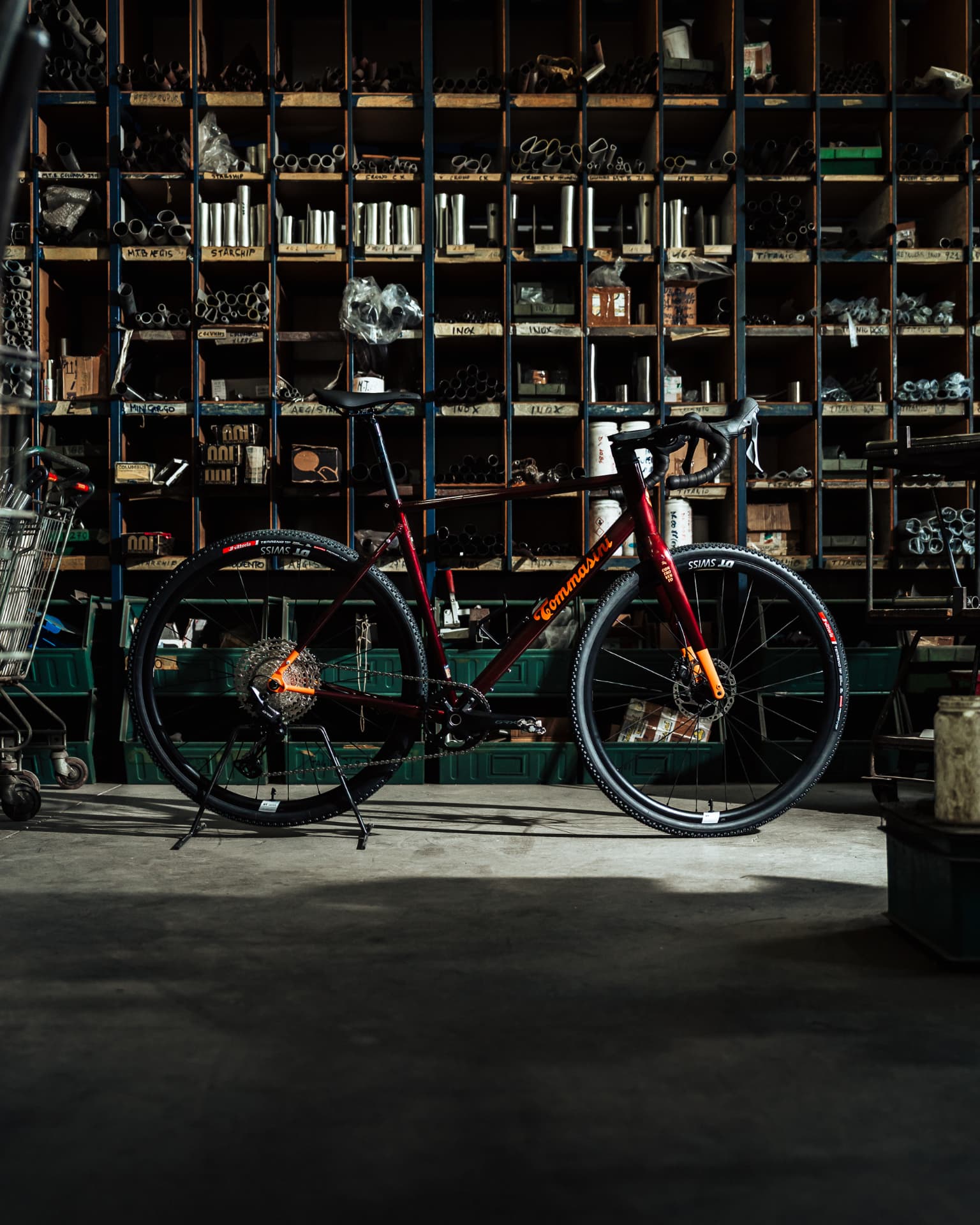 Tommasini Controvento Impanga steel frame in deep burgundy with orange details, side profile