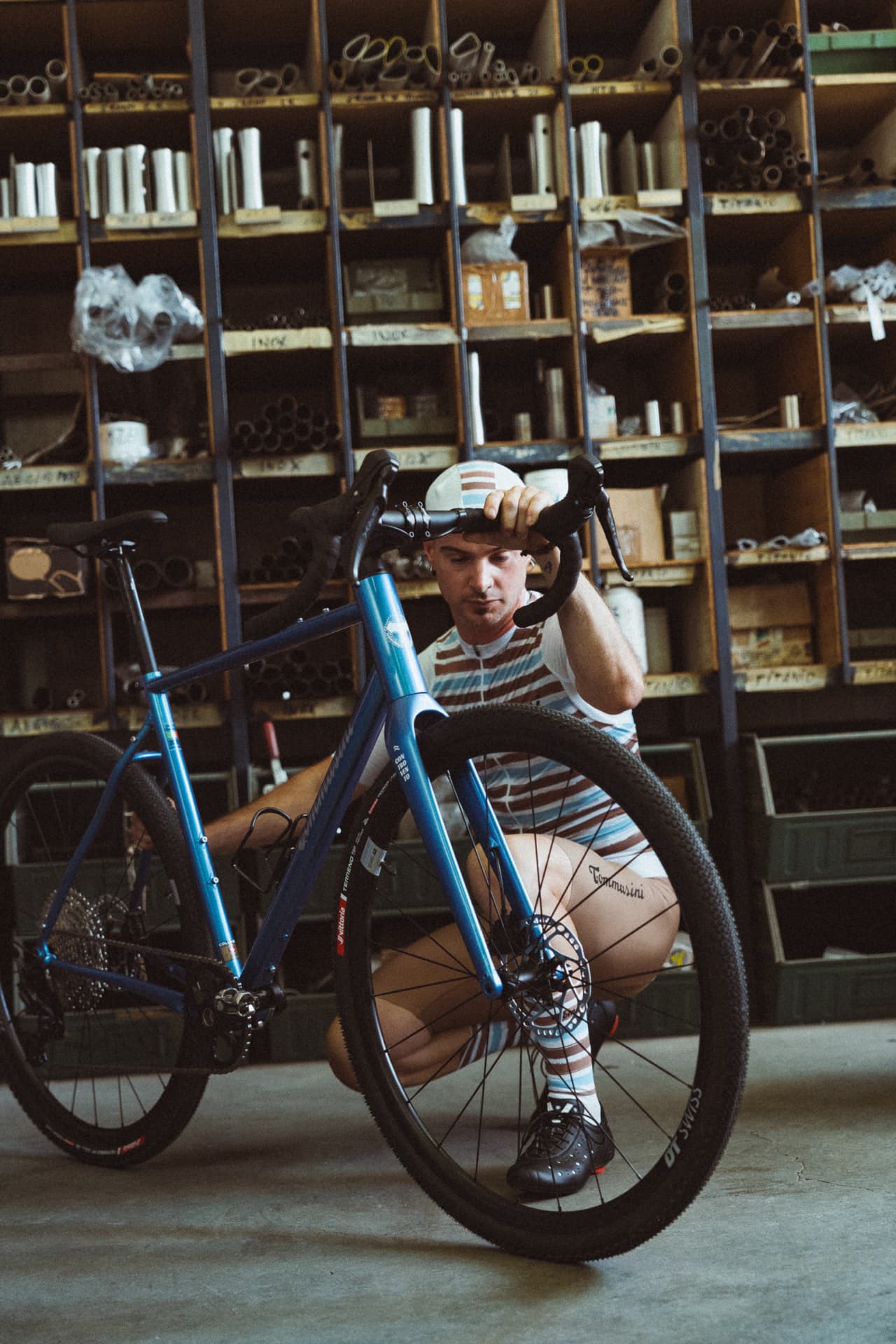Rider in striped Tommasini jersey crouching behind the blue Controvento in the workshop