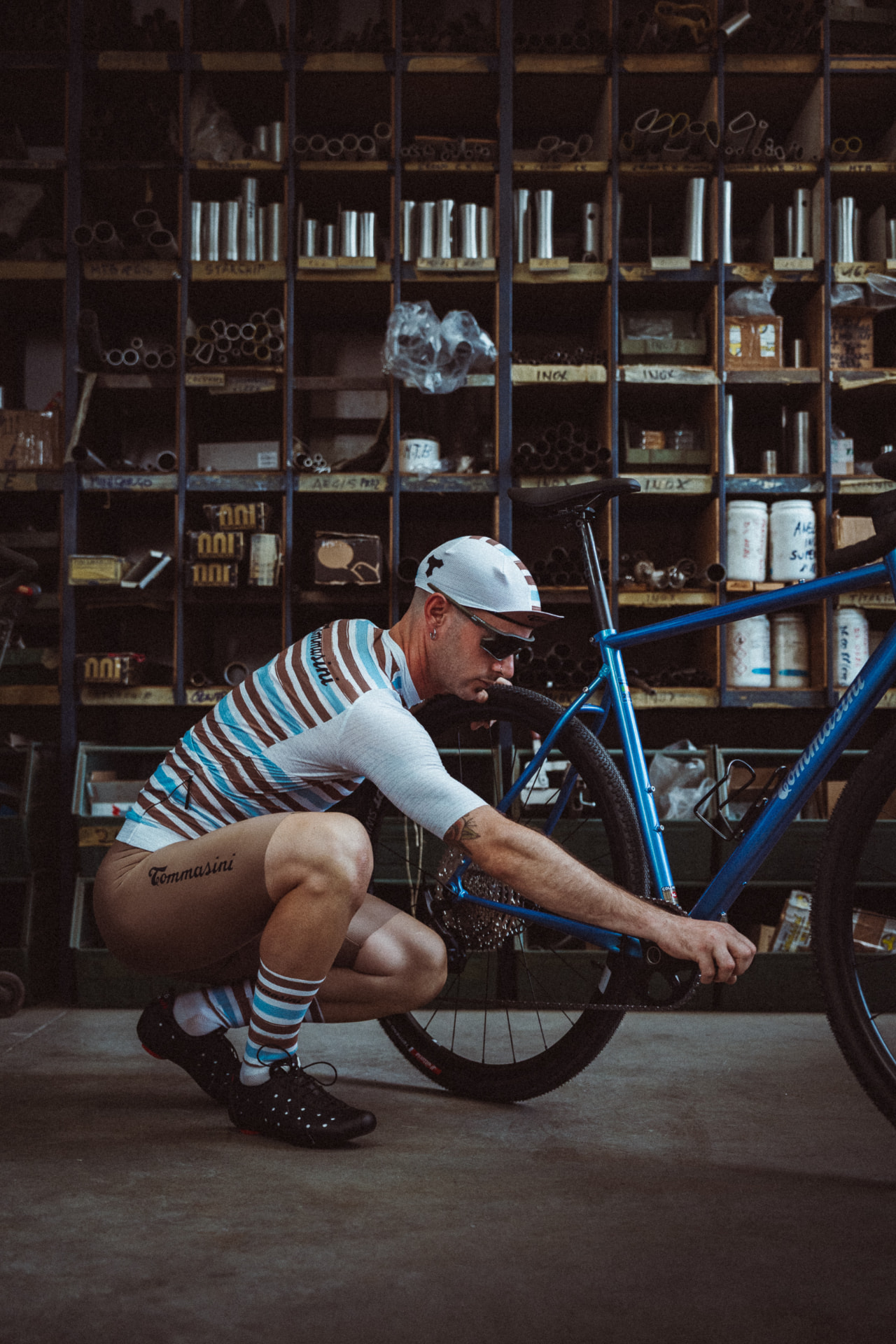 Rider crouching beside the blue Controvento in the Tommasini tubing store