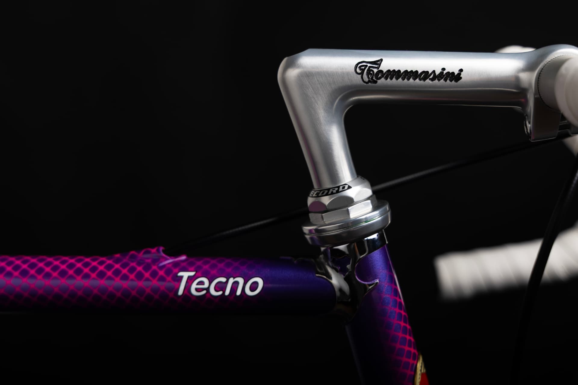 Close-up of the silver Tecno handlebar stem with engraved Tommasini signature