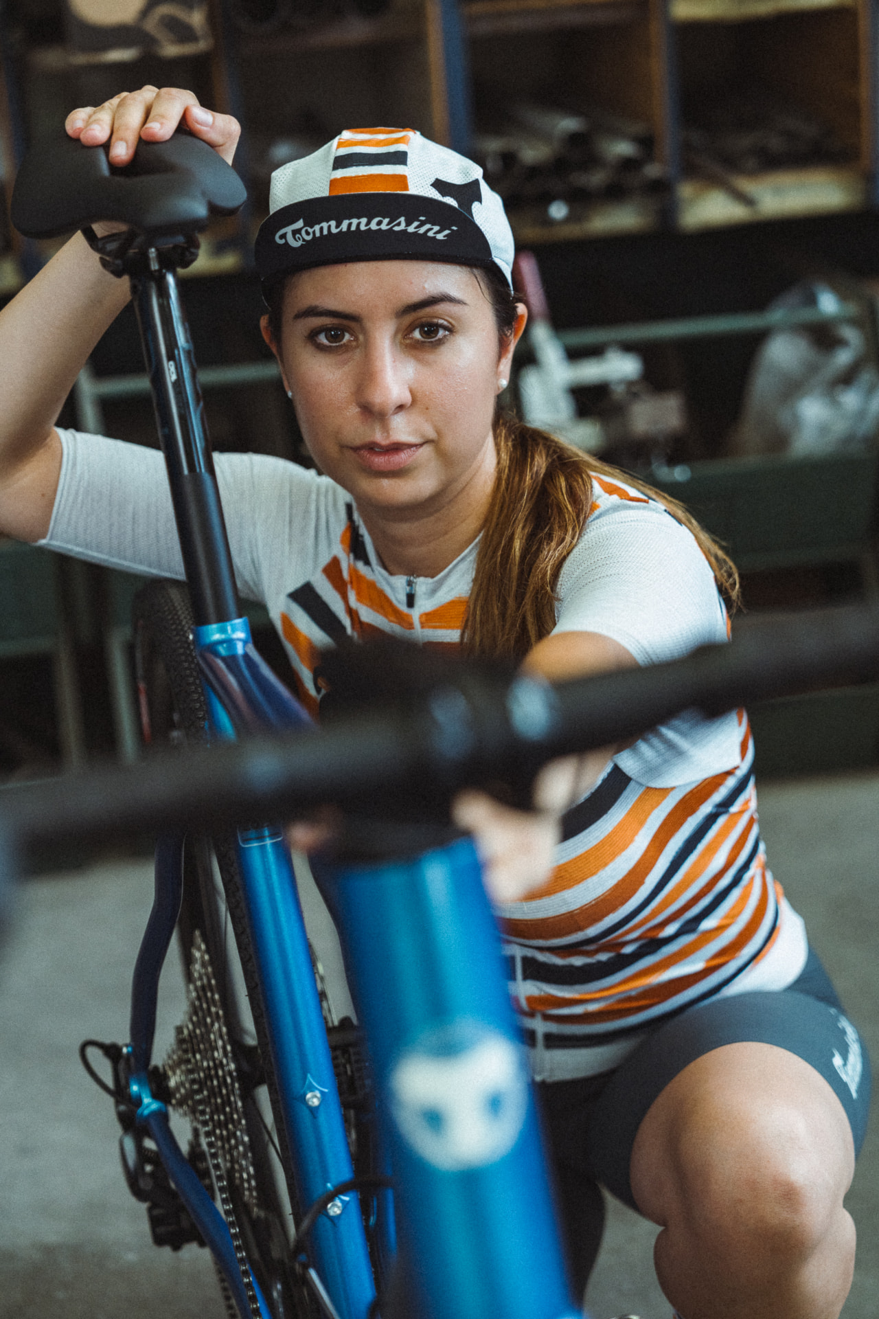 Rider in orange-striped Tommasini kit crouching beside the blue Controvento in the workshop